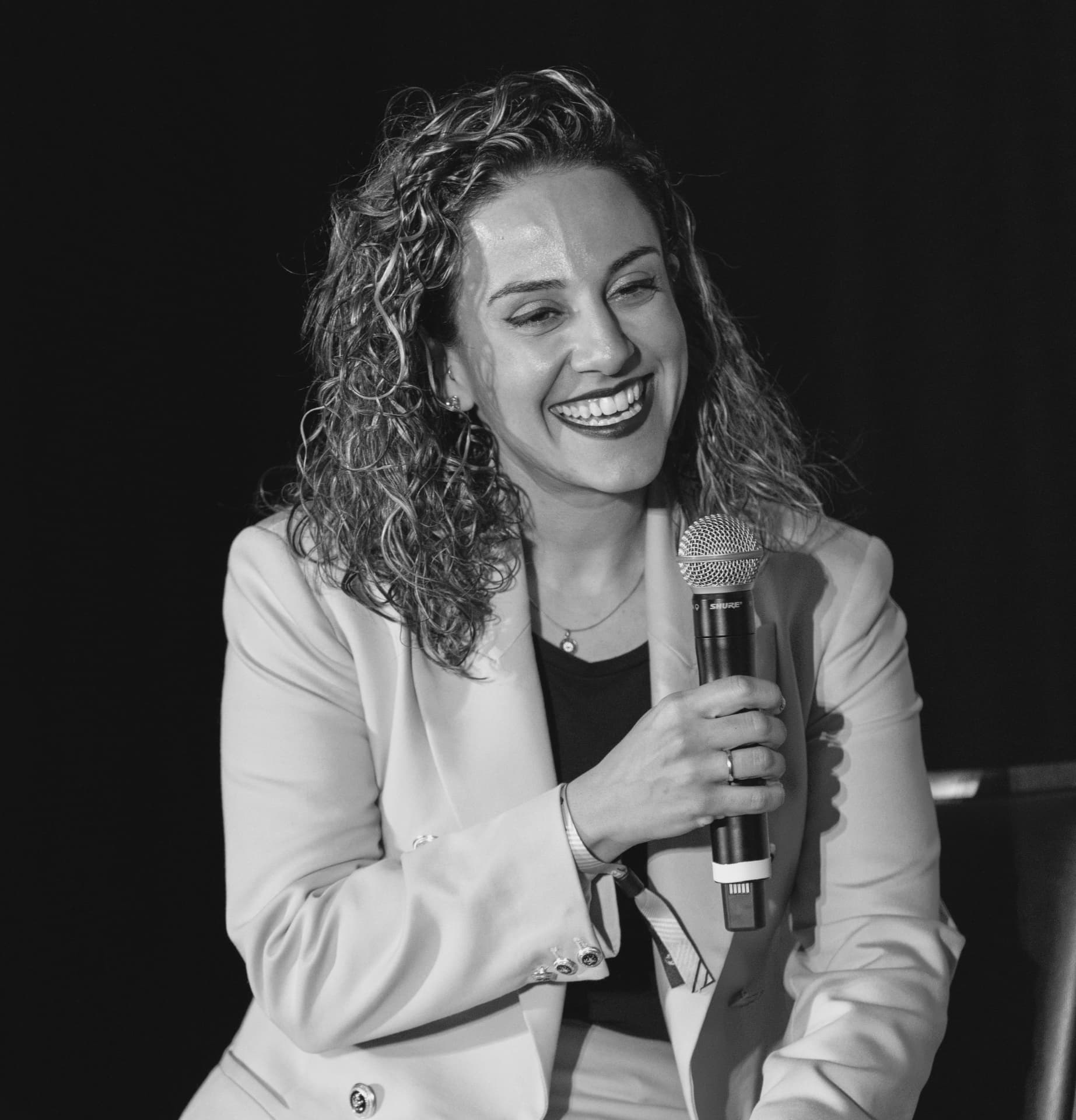 Farnoush Jafari speaking with a microphone at a live coaching event