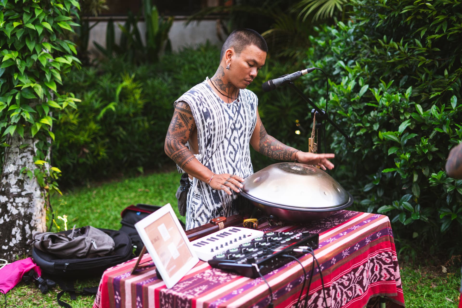 Musician playing a handpan in a garden during a live sound session.